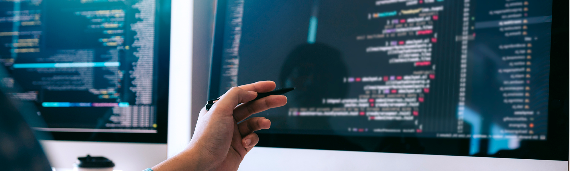 Kodea eta web-garapeneko elementuak erakusten dituzten monitore batzuekin lanean ari den pertsona baten irudia